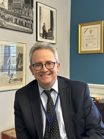 Burklow smiling, sitting in his Bldg. 1 office