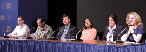 Several people seated behind a table on stage