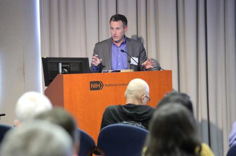 Perlis curls his fingers as he speaks at podium