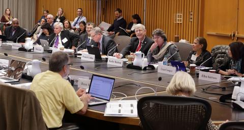 Committee members gather around table.