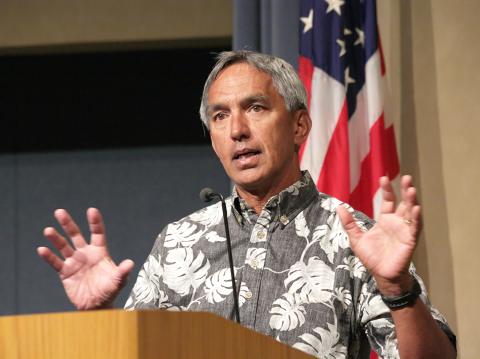 Nainoa Thompson with palms up speaks at podium