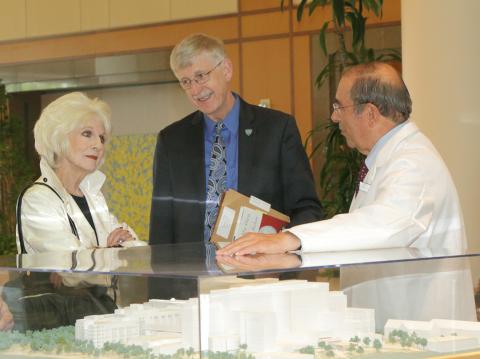 Rehm, Collins and Gallin talk next to CC model in the hospital atrium