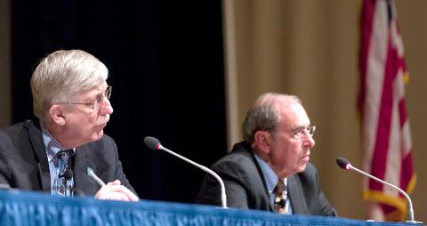 Seated at a panel table on stage, Collins and Gallin listen to people in the audience.