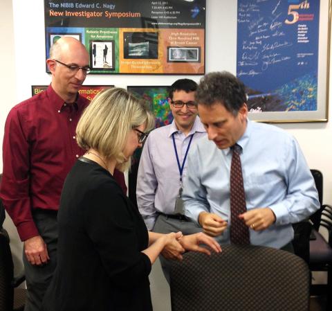 Dr. Mark Prausnitz and colleagues watch Jill Heemskerk try on the microneedle patch.