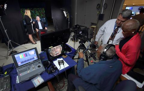 Dr. Collins sits in the studio surrounding by audio-visual equipment.