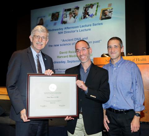 Collins presents plaque to David Reich as Daniel Reich stands by him.