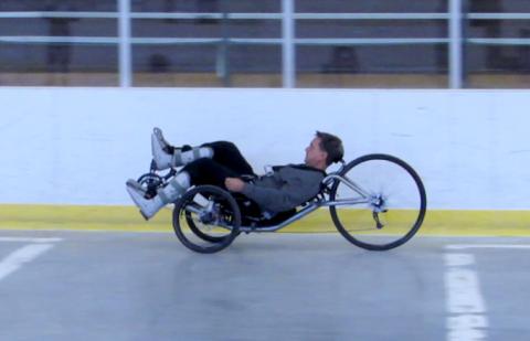 Mark Muhn rides around a track on a NIBIB-created tech-assisted three-wheeled cycle.