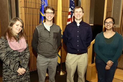 Four people smile into the camera.