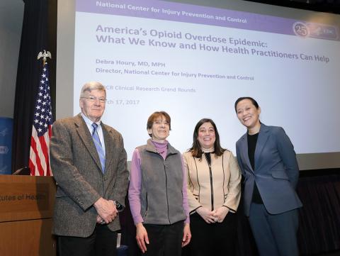 Four people gather for photo in front of title slide