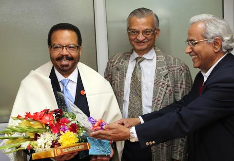 A smiling Pettigrew holds yearbook and bouquet of flowers, flanked by Kakodkar, and Tyagi