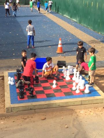 Children play on top of life-size, outdoor chess board
