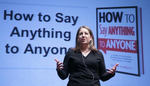 Harley stands with open hands in front of slide that reads: How to Say Anything to Anyone
