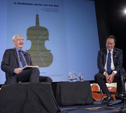 Collins sits on stage with Yo-Yo Ma