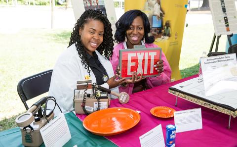 Two smiling ORS employees hold up a red exit sign.