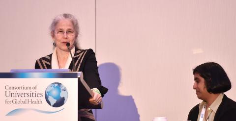 Wasserheit speaks at podium as Anand looks on.