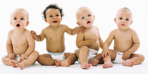 Four babies sit together looking off in the distance