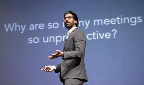 Pittampalli speaks in front of a slide that asks "Why are many meeting so unproductive?"