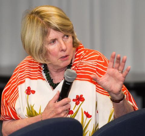 Jamison holds microphone while speaking to audience.