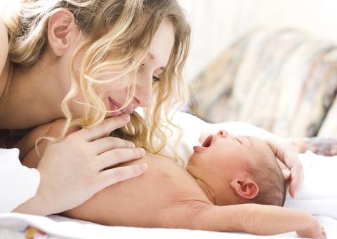 A woman holds, admires her yawning baby