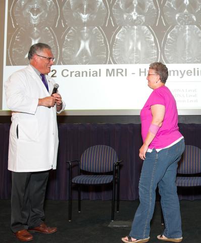 Standing,Toro speaks with patient Kelley on stage 