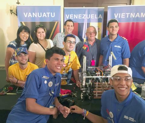 Robotics kids and NIBIB staff smile, gather around model.