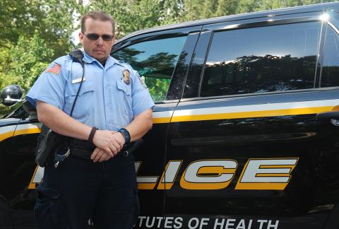 Corporal McKee stands in front of police cruiser.