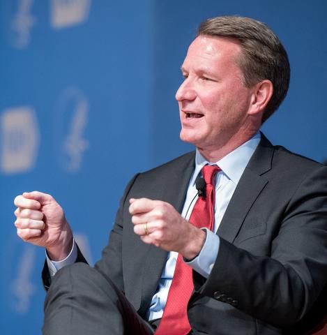 Sharpless gestures with his hands as he speaks to the audience.