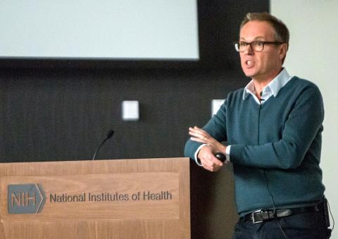 Dr. Gero Miesenböck lectures at a podium.