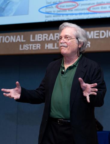 Dr. Alan Kay gestures with hands at NLM lecture.