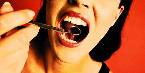 Looking into a woman's open mouth with a dentist's mirror