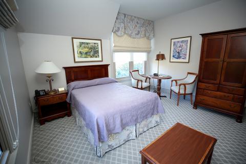 View of room with double bed, nightstand, table and 2 chairs, and wooden wardrobe