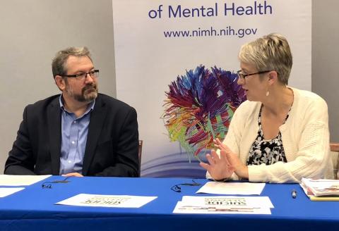 Gordon and Pearson seated behind table, in conversation