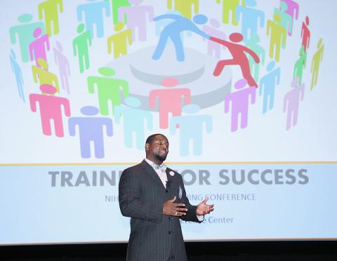 Caldwell speaking in front of a projected slide.