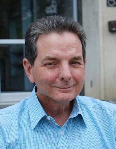 Kevin Sweeney, sitting outdoors on steps.