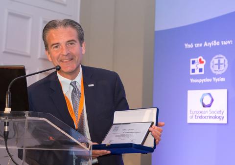 Dr. Constantine Stratakis holds award at ceremony in Athens.