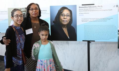 Dr. Emmeline Edwards of NCCIH and her granddaughters next to poster with her photo