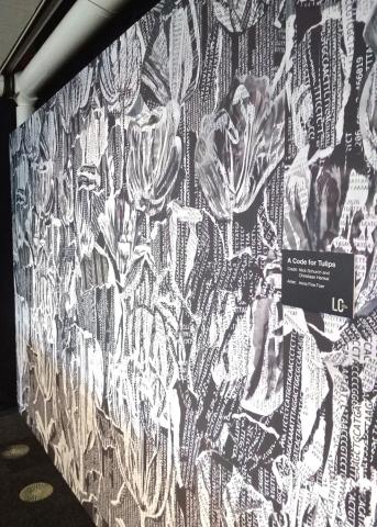 A wall-size reproduction of “A Code for Tulips,” which features black text on white background shaped like tulips
