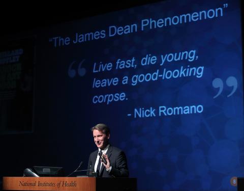 Dr. Sharpless in front of slide with the quote Live fast, die young, leave a good-looking corpse.