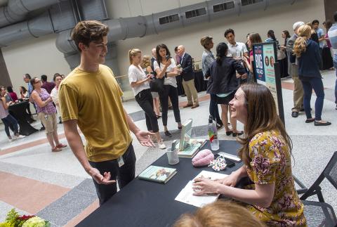 Thomson sits at a table chatting with a guest while others wait in line to meet her on the FAES terrace.