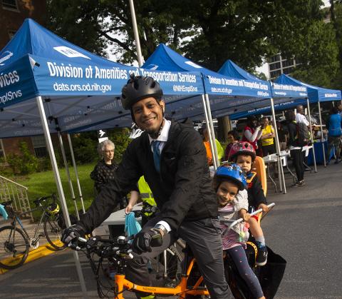 A smiling Dr. Chittiboina on his electric cargo bike with his two young kids in tow