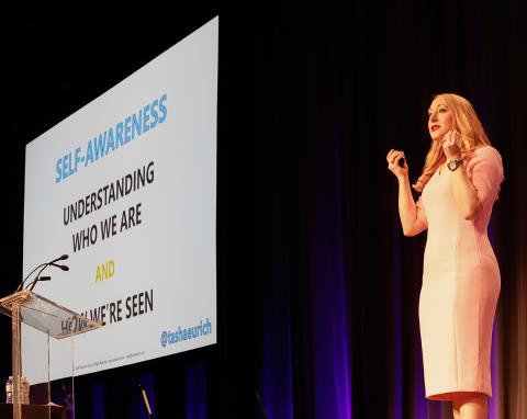 Dr. Eurich stands on stage beside slide that reads: Self-Awareness, Understanding Who We Are and How We're Seen