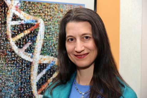 Closeup of Segre with double helix art shown on wall behind her