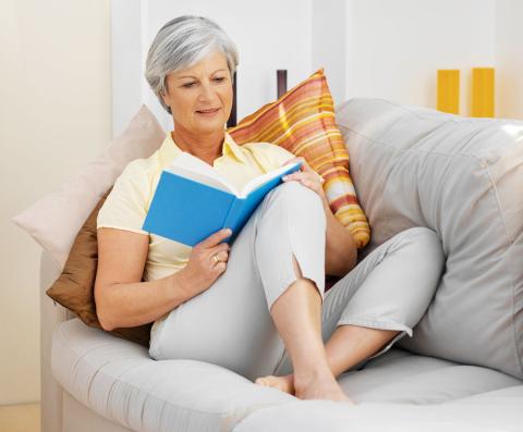 Woman with gray hair reads on sofa