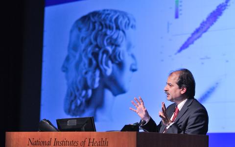 Ioannidis at podium with slide projected behind him