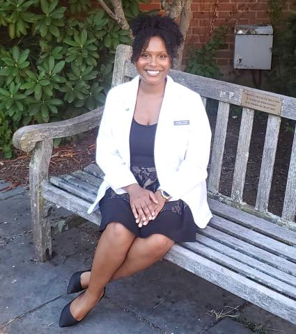 Young woman in labcoat seated on wooden bench