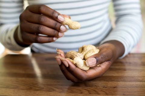A man holds peanuts in his hand.