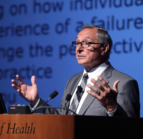 Dr. DiClemente holds up hands while speaking at podium.