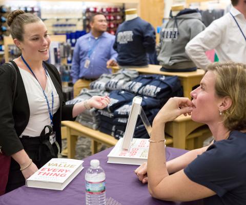 Seated at a table, Mazzucato talks with a woman in the bookstore. 
