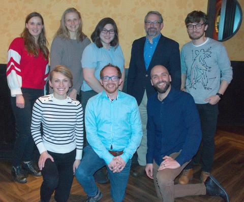 Group shot of 8 people smiling into camera