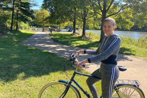 Fitzhugh on her bike with the trail and a lake behind her